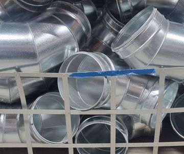 Galvanised metal ductwork elbows and straight sections inside a wire cage.