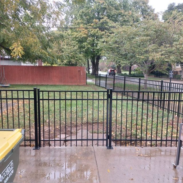 A black fence with a yellow trash can in front of it | Louisville, KY | Lancaster Fencing