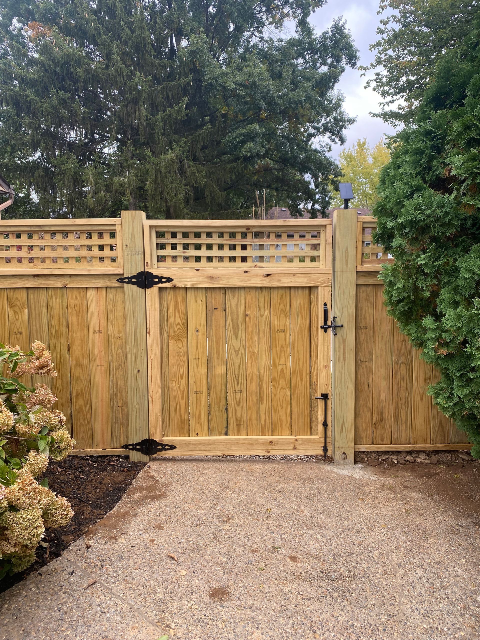 A wooden fence with a gate in the middle of a gravel driveway.  | Louisville, KY | Lancaster Fencing