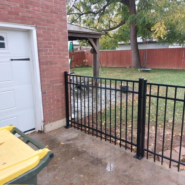 A yellow trash can sits next to a black fence | Louisville, KY | Lancaster Fencing