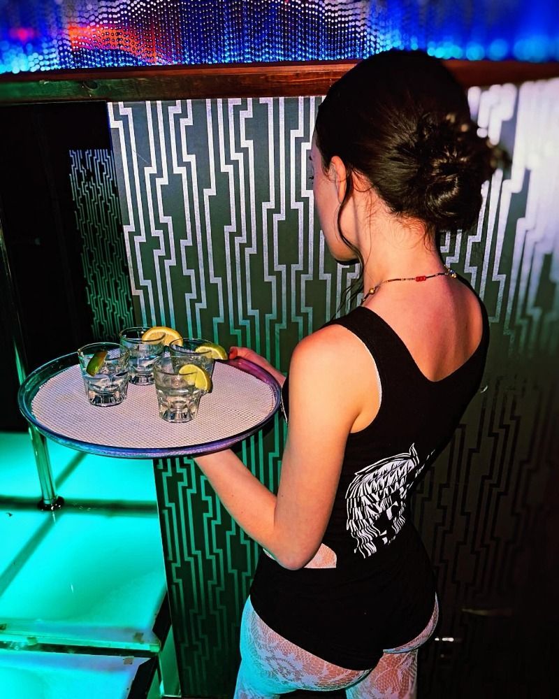Woman carrying a tray of tequila shots in a nightclub.