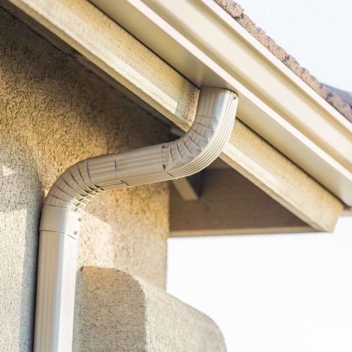 Beige gutter system on a stucco wall of a building.