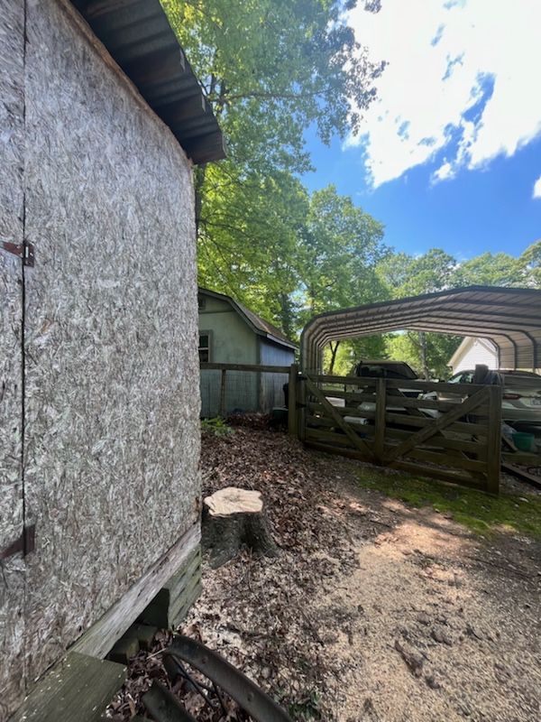 A car is parked under a canopy in the backyard of a house.
