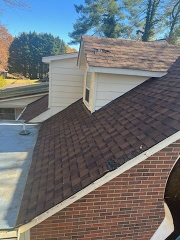 The roof of a house with a brick wall and a brown roof.