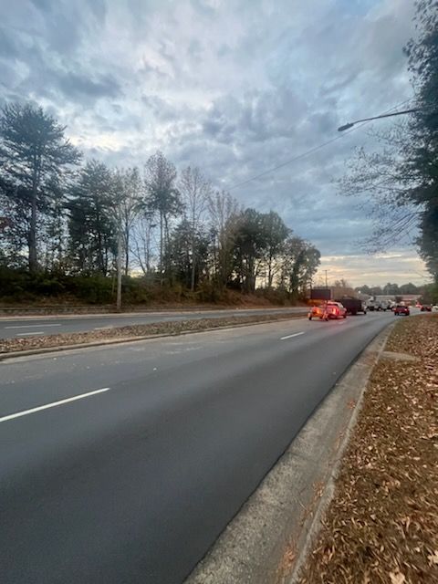 A car is driving down a road with trees on the side.