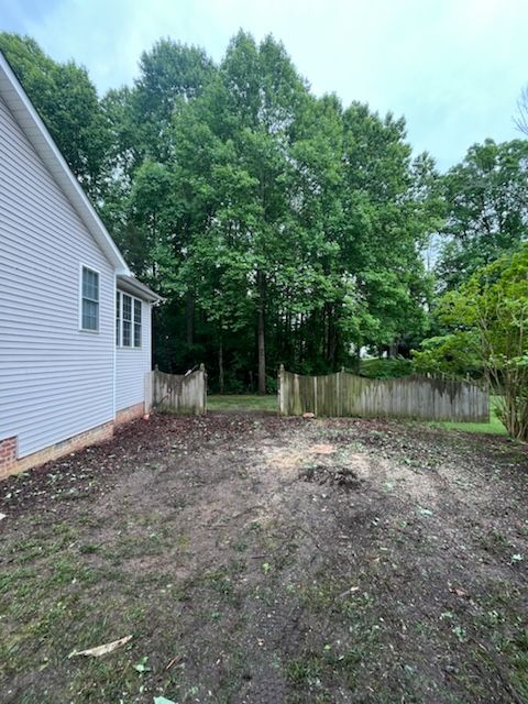 The backyard of a house with a fence and trees in the background.