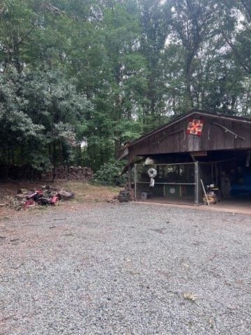 A wooden building with a fire pit in front of it in the woods.