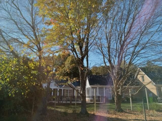 A white house is surrounded by trees on a sunny day
