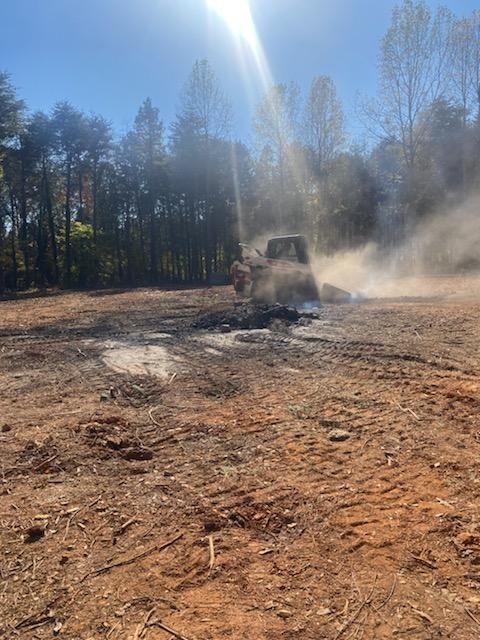 A truck is driving through a dirt field with trees in the background.