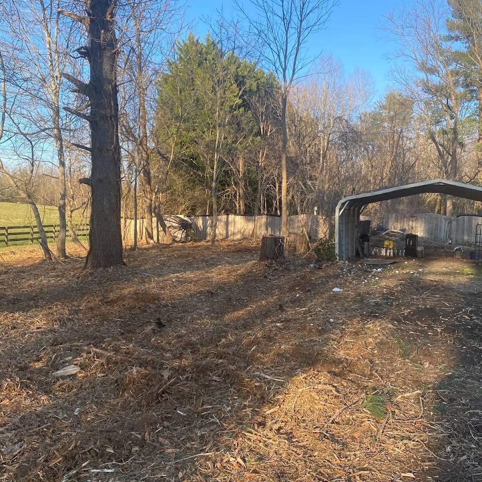 There is a shed in the middle of a field with trees in the background.
