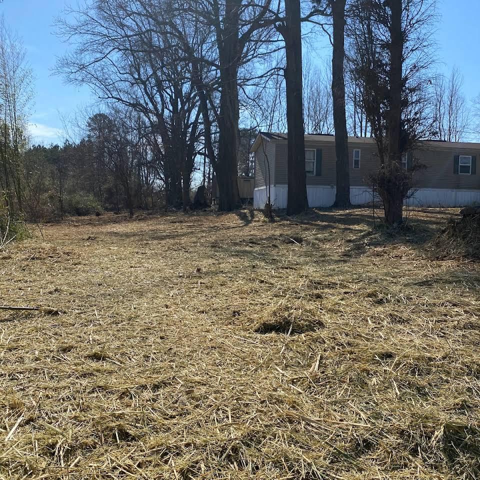 A field with trees and a mobile home in the background