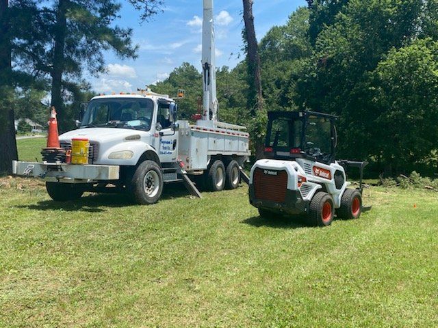 A truck and a forklift are parked in a grassy field.