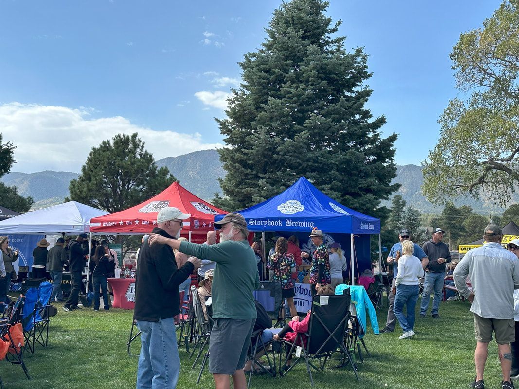 People at an outdoor event with tents and mountains in the background.