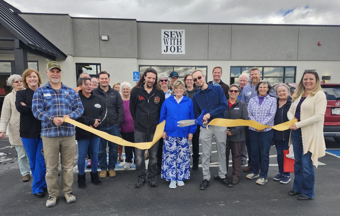 People cutting ribbon at Sew-n-Joe grand opening; exterior shot, gray building, overcast sky.