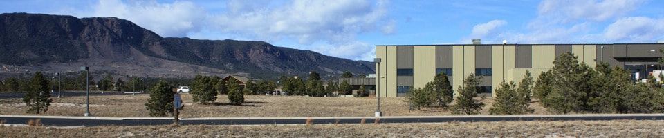 Distant mountain range behind a field with a building on the right. Person walking towards the left side.