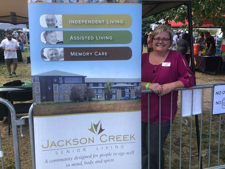 Woman at a senior living booth promoting independent living, assisted living, and memory care.
