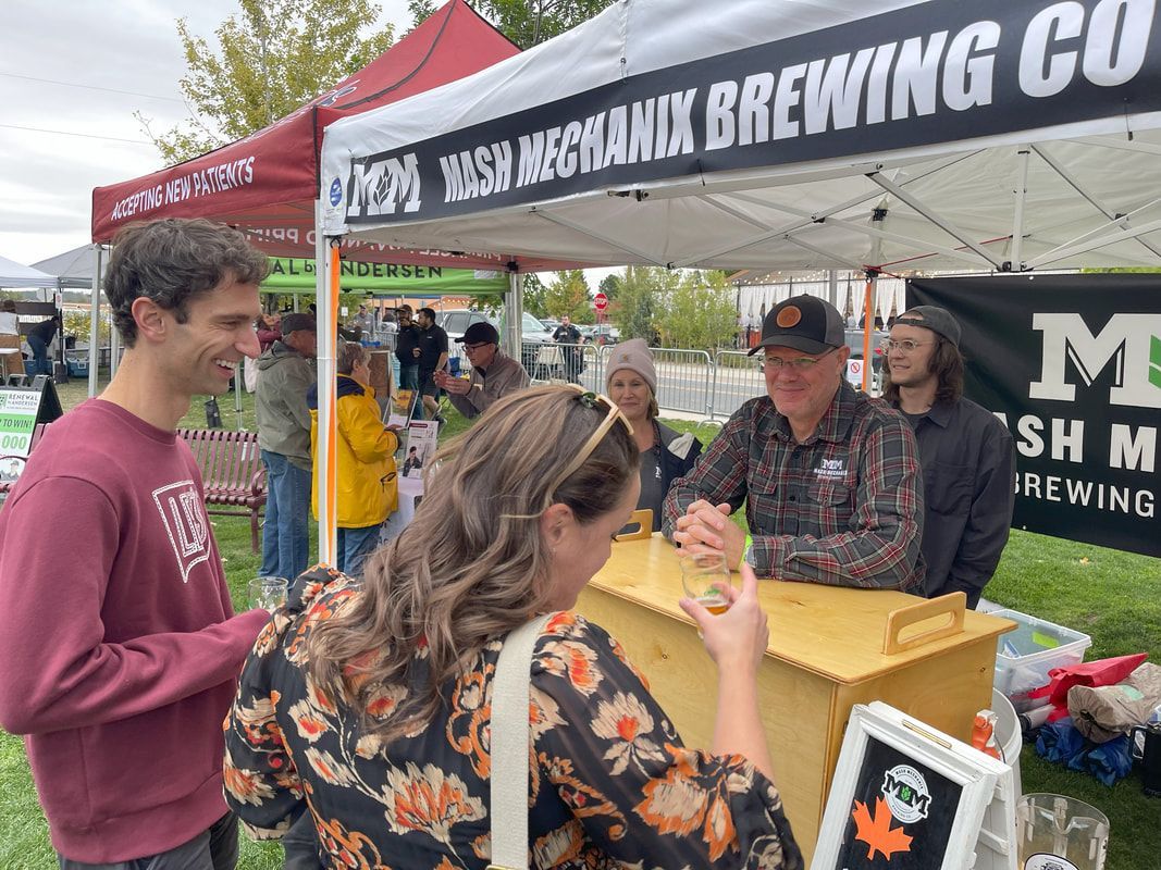 People at a beer stand. Man in plaid serves others. Tent says 