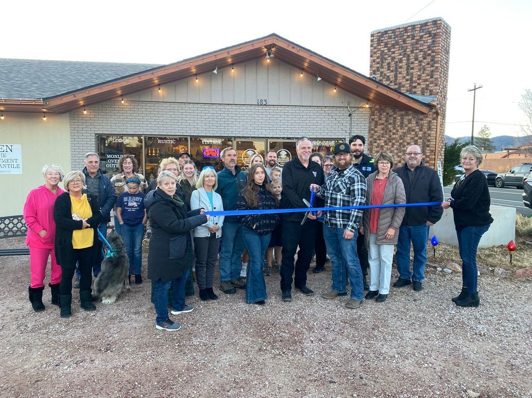 Group of people at a ribbon-cutting ceremony outside a building with a stone chimney.
