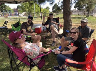 Group of friends relaxing in chairs outdoors under shade.