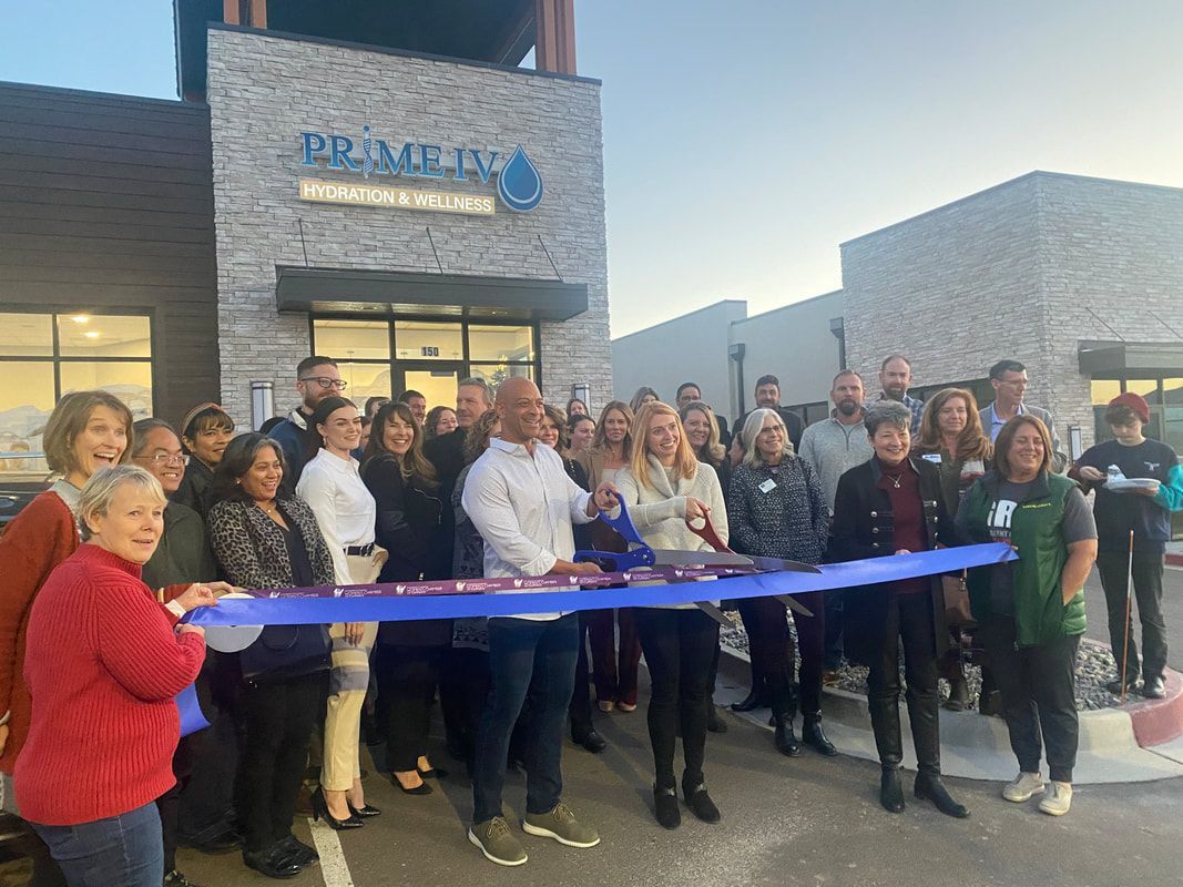 Group cutting ribbon at a grand opening of a building with a blue sign.