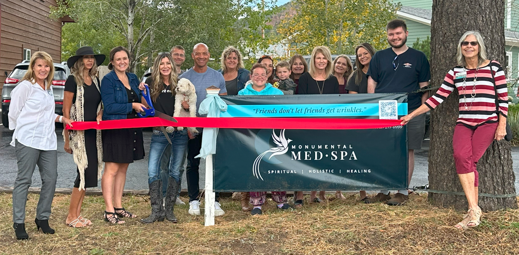 People cutting a ribbon at the grand opening of a spa; a sign with a horse logo is visible.