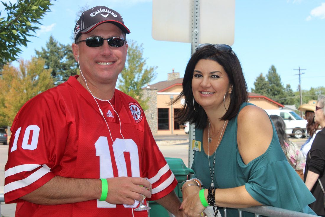 Man in red jersey and woman in teal top smile at camera outdoors.