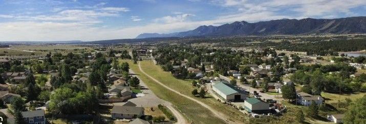 Aerial view of a town with mountains in the background under a blue sky.