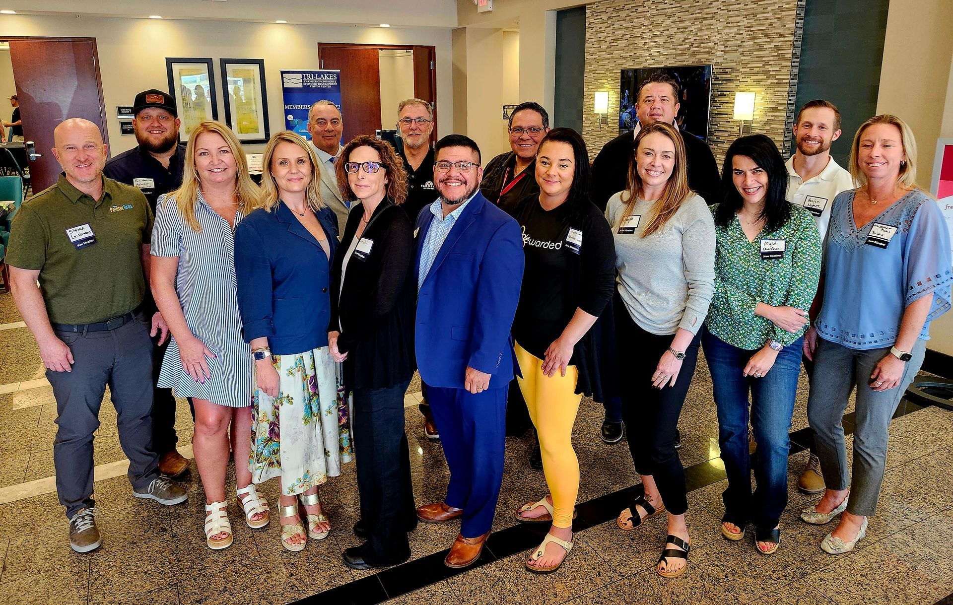 Group of people pose in front of a Texas Roadhouse restaurant; sunny day.