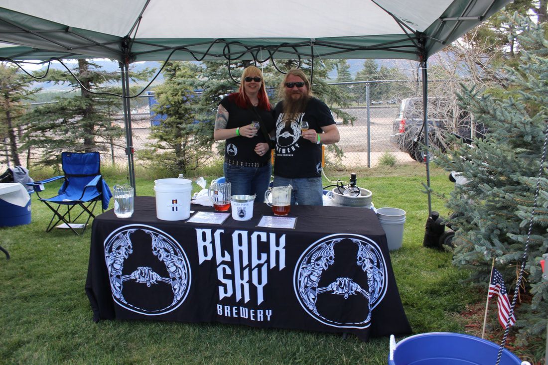 Two people behind a Black Sky Brewery booth at an outdoor event.