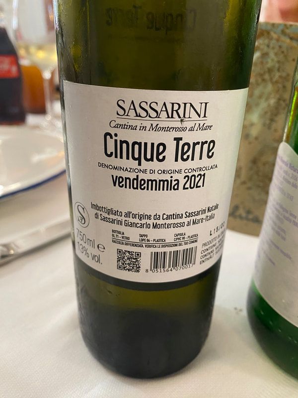Close-up of a bottle of Sassarini Cinque Terre wine, vendemmia 2021, green glass, white label.