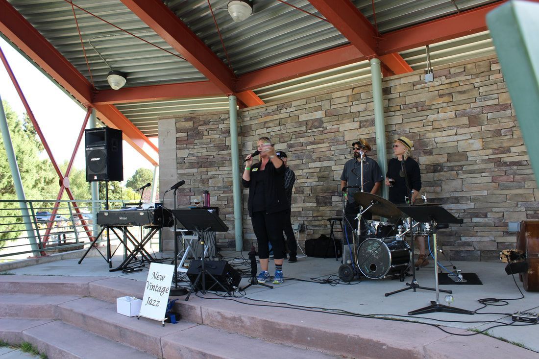 A band performs on an outdoor stage with a brick wall background.