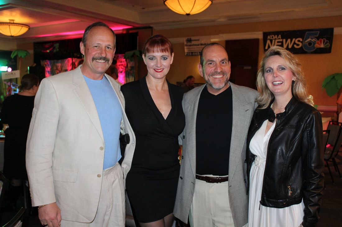 Four people, two men and two women, smiling and posing indoors.