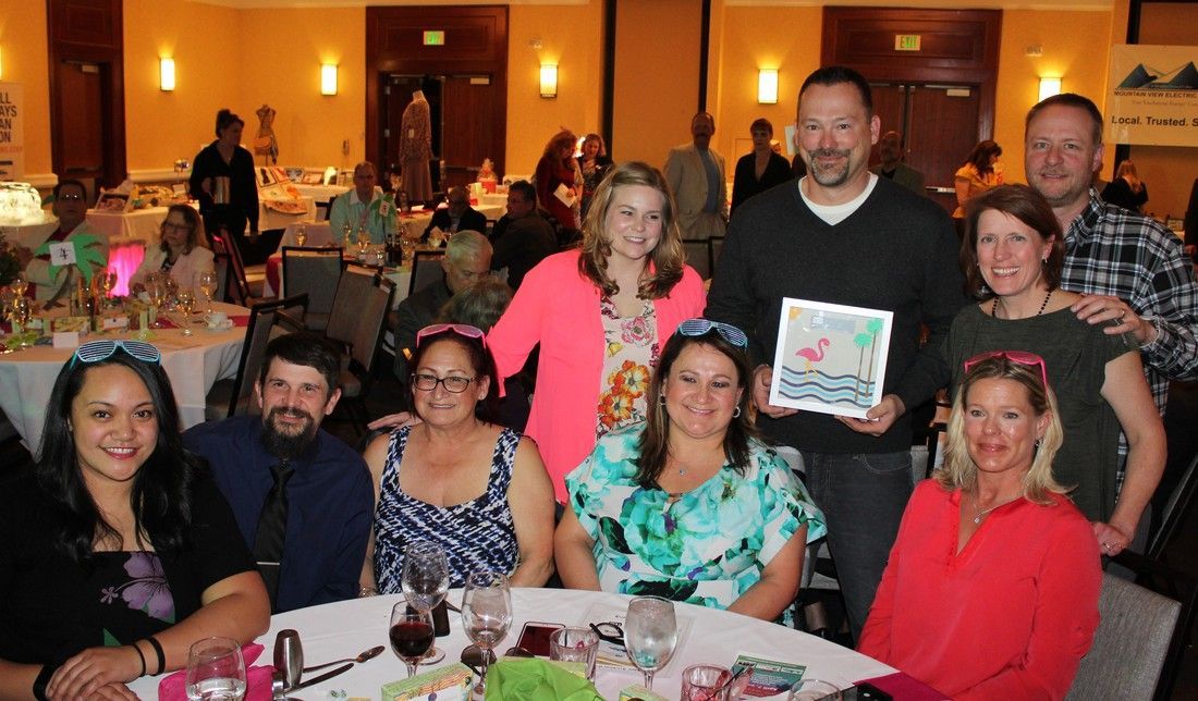 Group of people at a formal event, some holding an award, smiling.