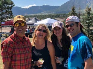 Four people smile, posed outdoors with mountains in the background.