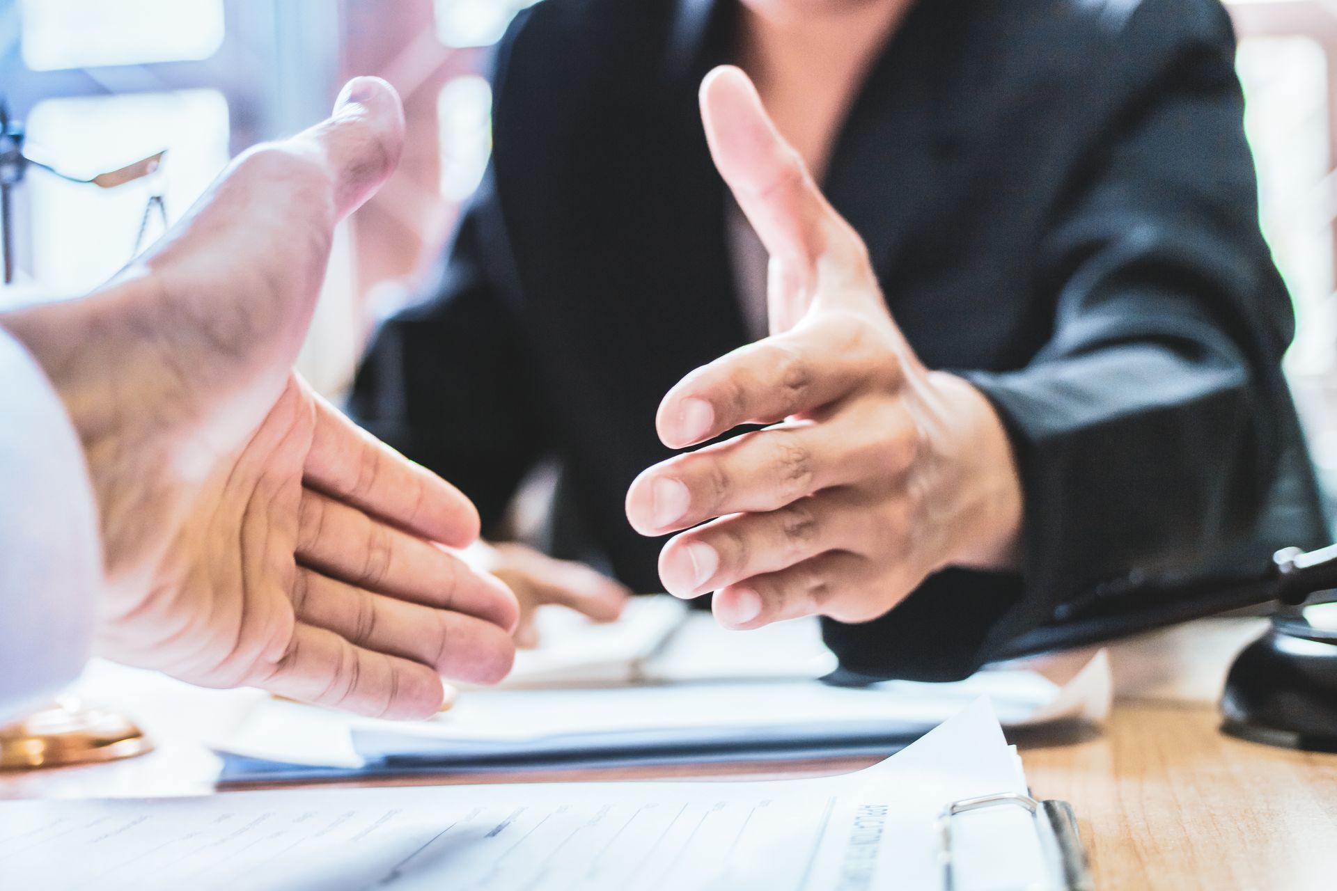 A man and a woman are shaking hands over a table.