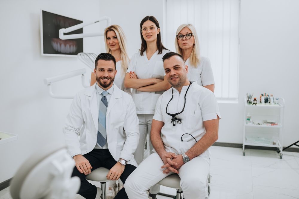 A group of dentists are posing for a picture in a dental office.