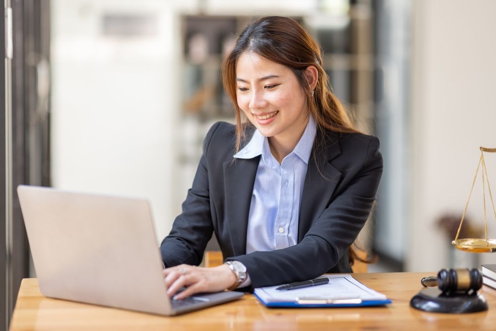 A young Asian woman typing on a laptop using JANO Tech's court case management software.