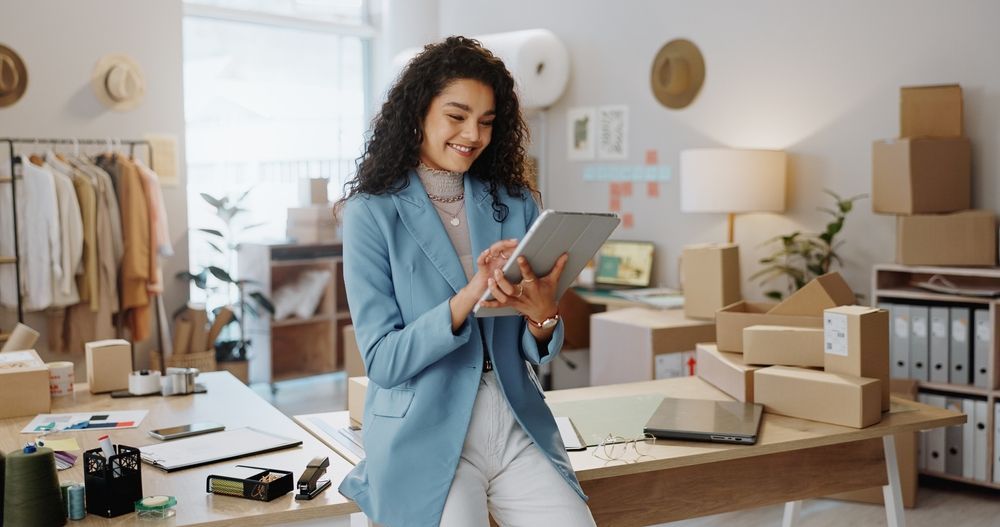 A woman is sitting at a desk using a tablet computer.