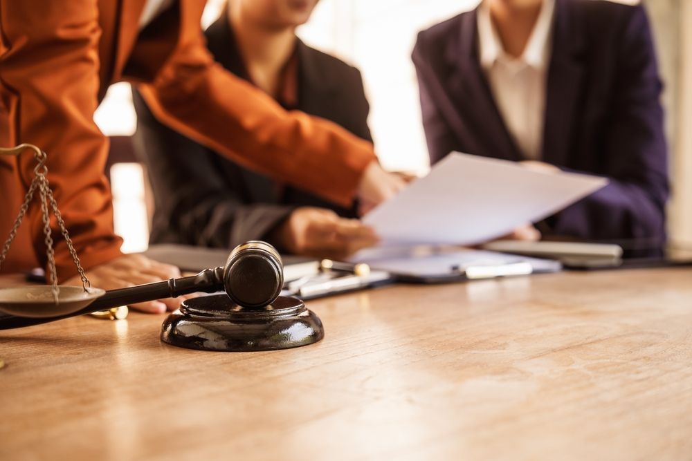 A judge 's gavel is sitting on a wooden table next to a scale of justice.