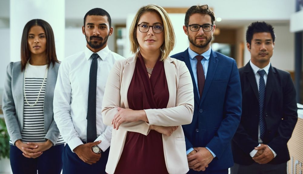 A group of business people standing next to each other in an office.
