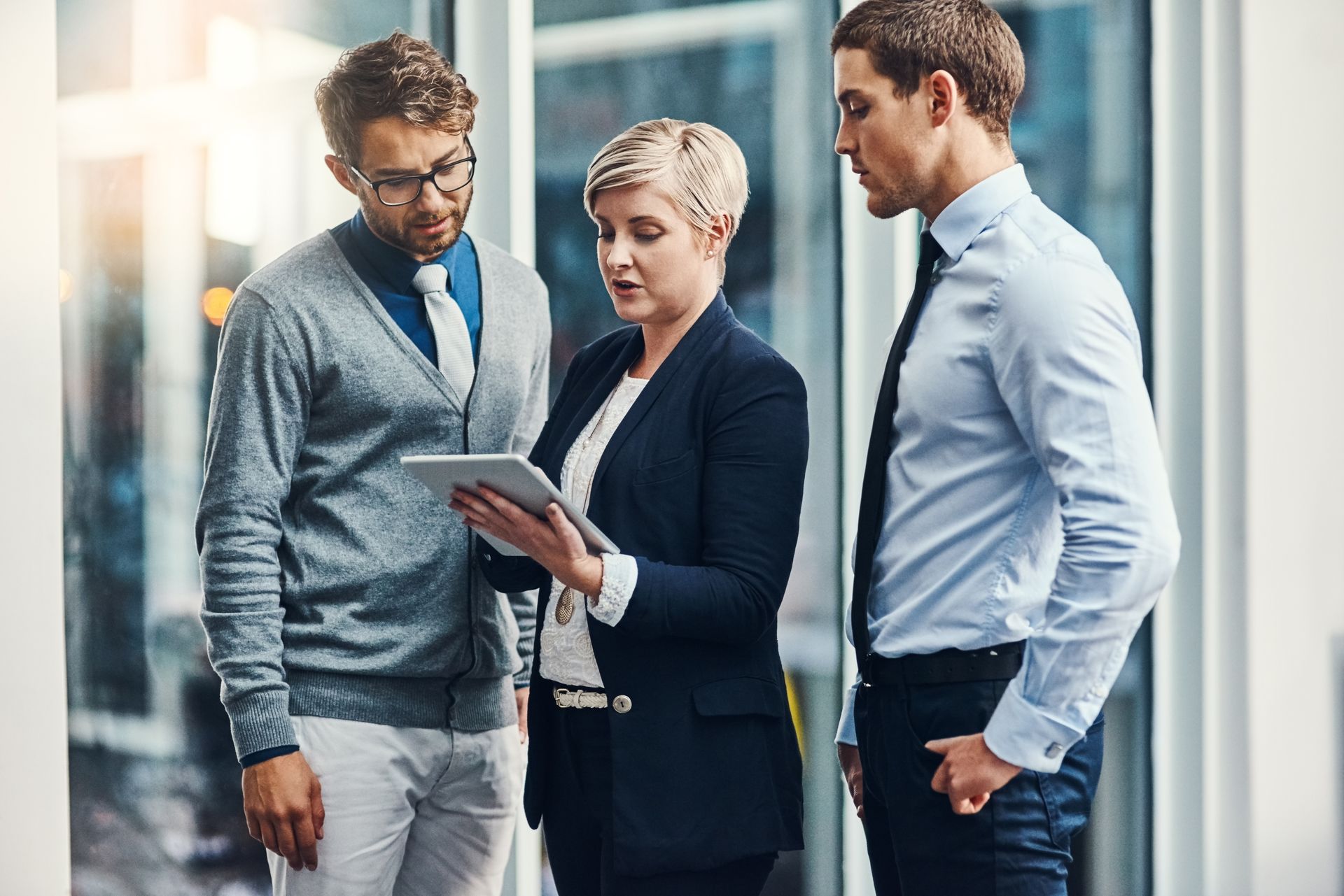 A group of business people are standing next to each other looking at a tablet.