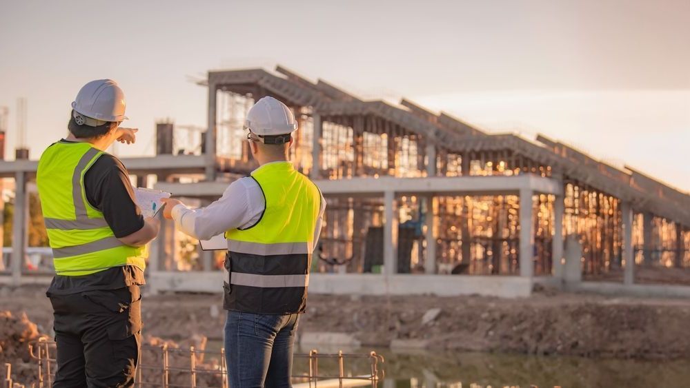 Two construction workers are looking at a blueprint at a construction site.