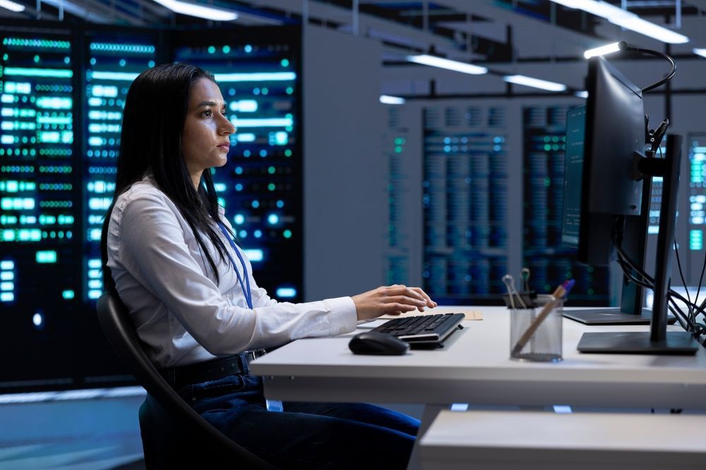 A woman is sitting at a desk in front of a computer.