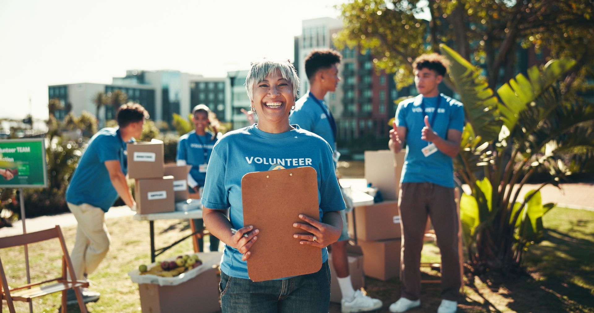 A group of volunteers are standing in a park holding a clipboard.