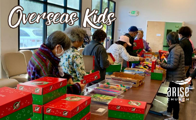 A group of people are sitting around a table filled with boxes.