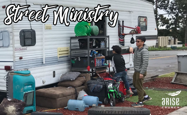 A group of people are standing in front of a trailer that says street ministry.