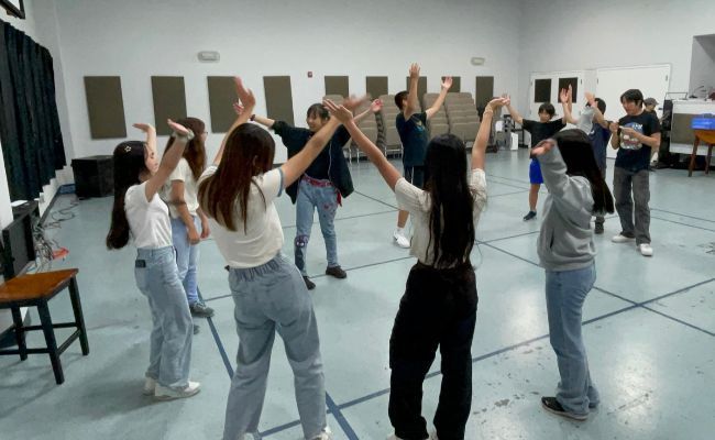 A group of young people are dancing in a circle in a room.