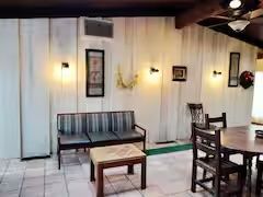 A living room with a couch , table , chairs and a ceiling fan.