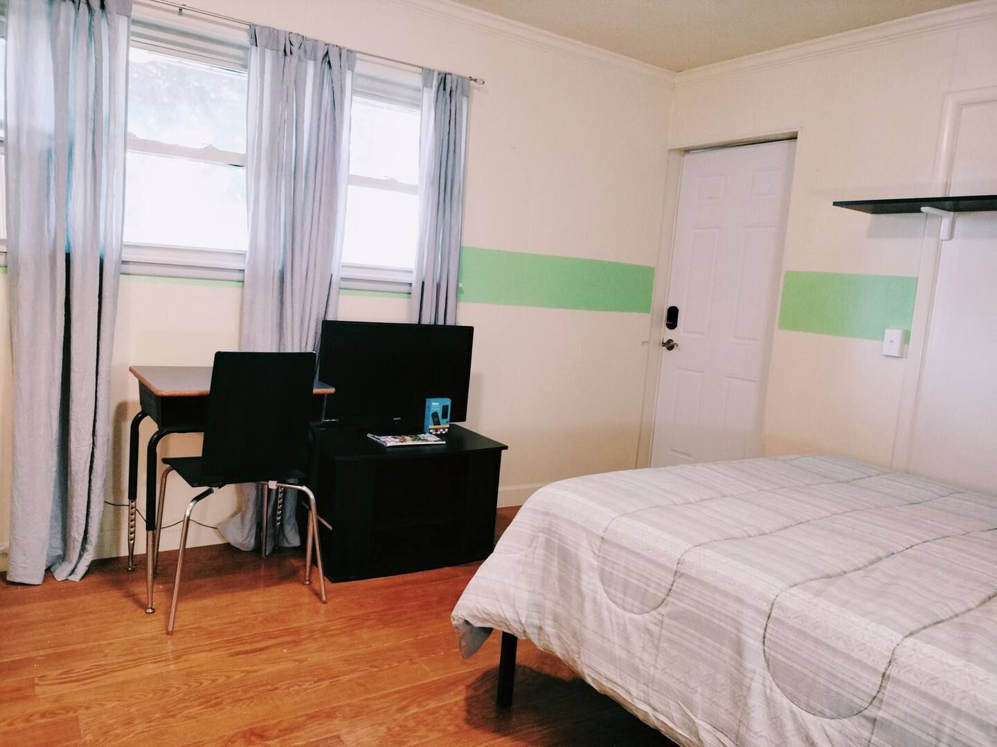 A bedroom with a bed a desk and a computer