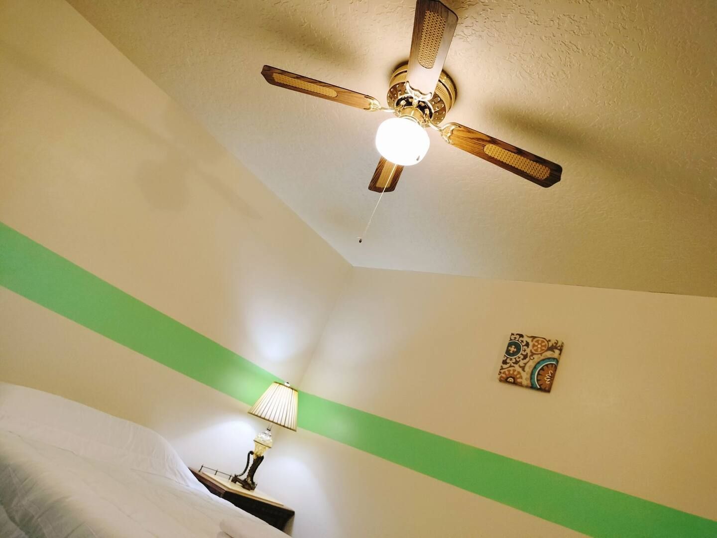 A bedroom with a ceiling fan and a lamp